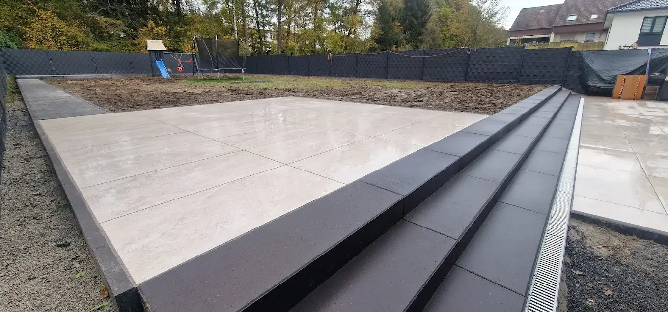 Großzügige Terrasse mit hellen Großformatplatten und dunklen Stufen