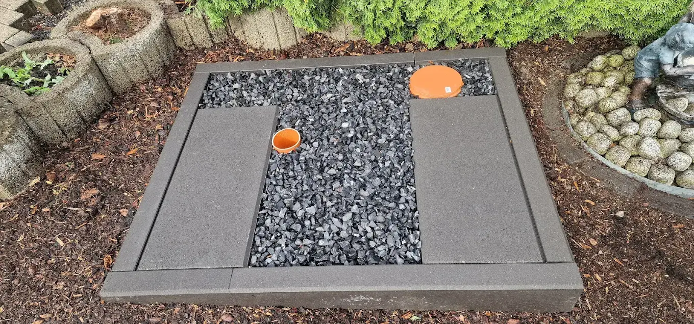 Wärmepumpen-Fundament mit Kiesbett und Rohranschlüssen im Garten