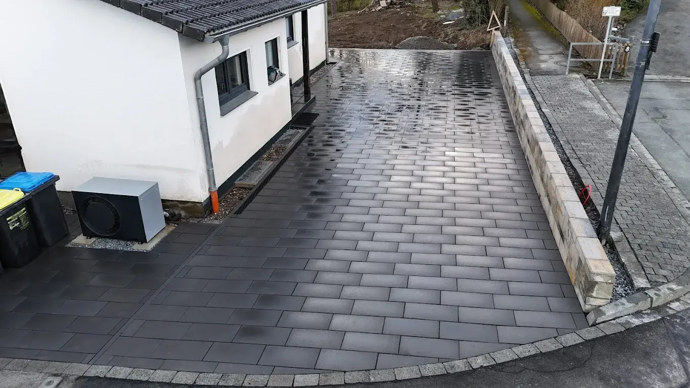 Dunkle Pflastereinfahrt vor einer weißen Garage