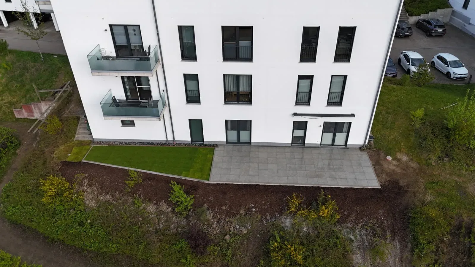 Nachher: Nachher: gepflasterte Terrasse mit Rollrasen am Mehrfamilienhaus