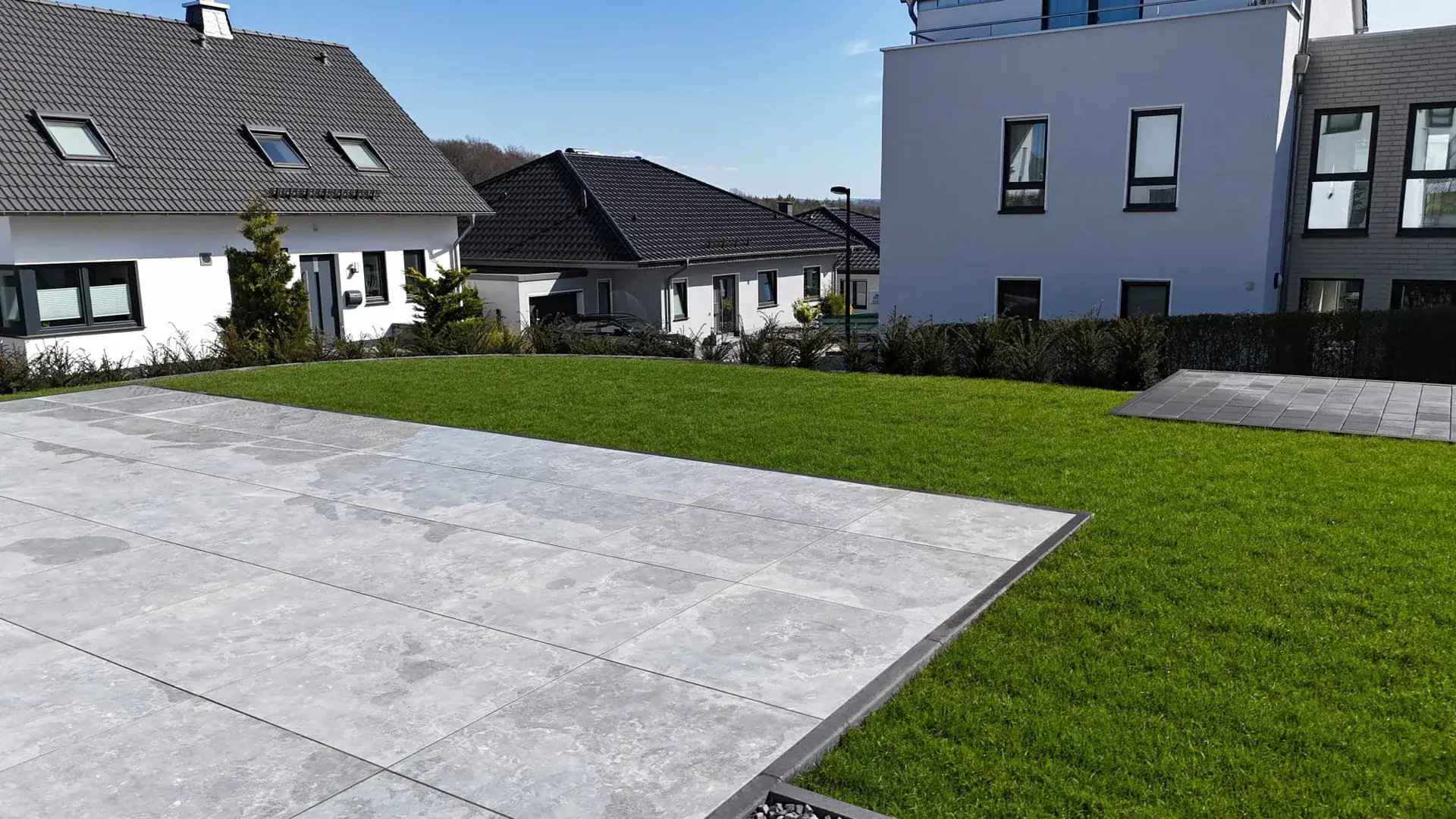 Große Keramikterrasse mit Rasen am Neubau
