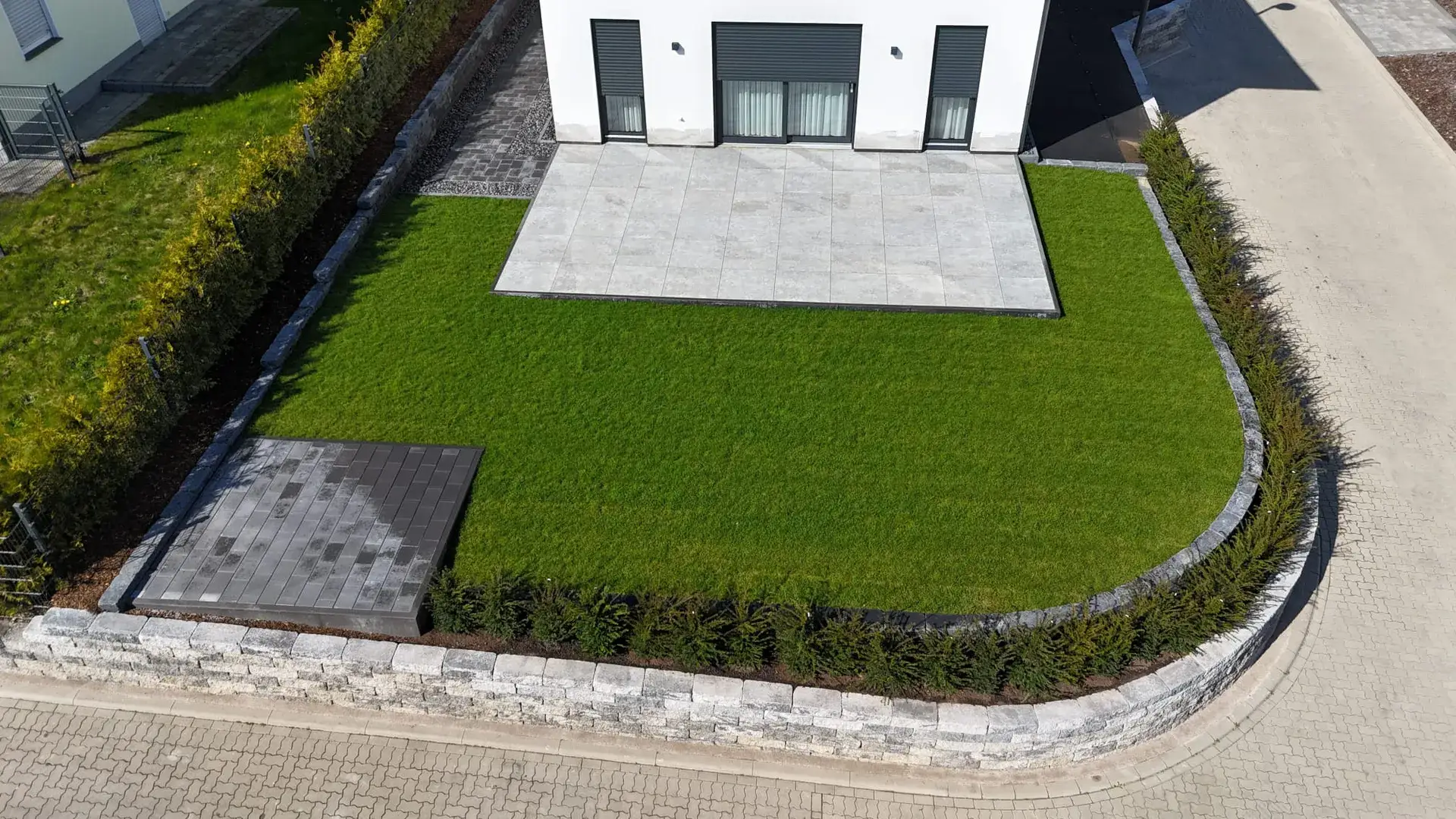 Luftbild: Terrasse mit geschwungener Natursteinmauer und Rasen