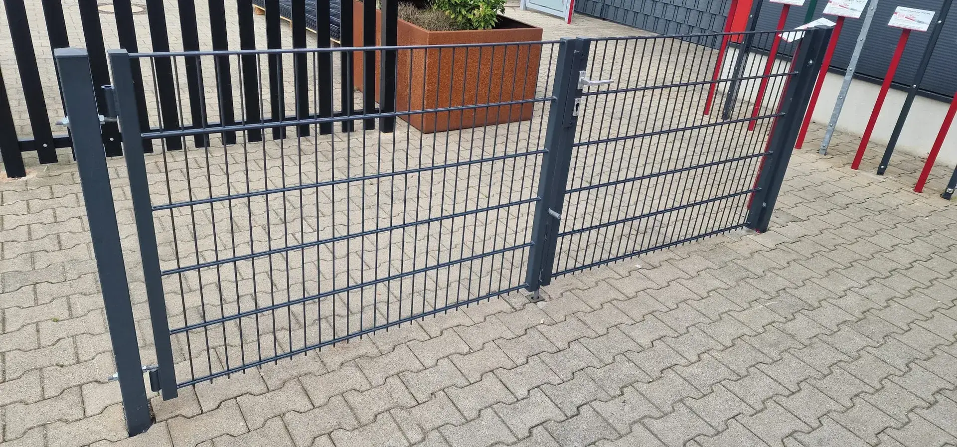 Anthrazitfarbenes Stabtor an gepflasterter Einfahrt