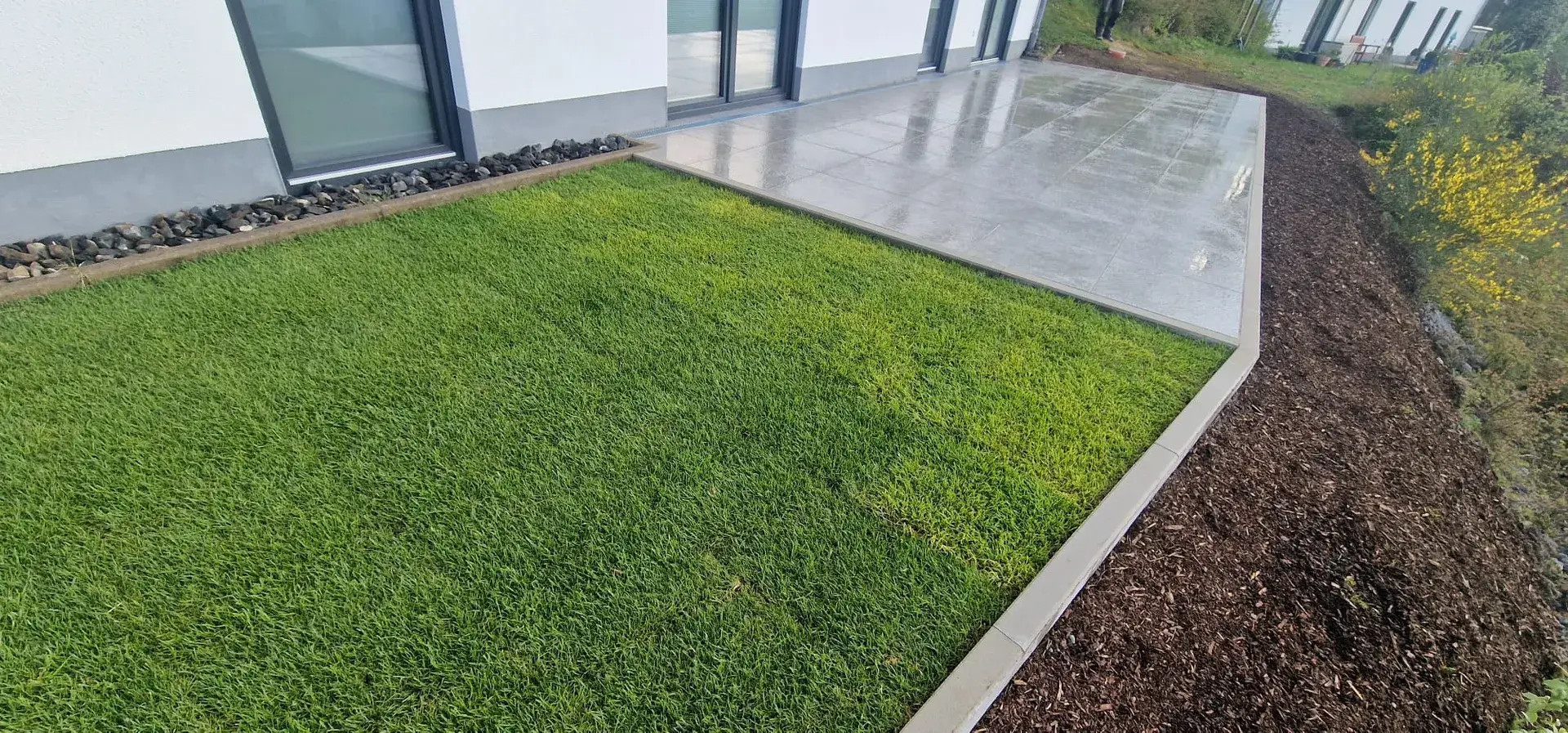 Rollrasenkante an moderner Terrasse mit Mulchbeet