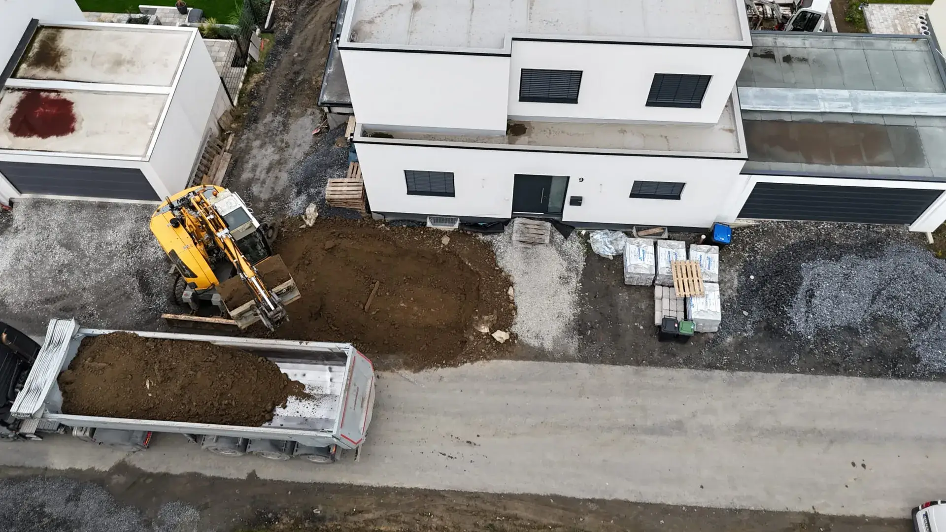 Luftbild: Radlader und Container bei Erdarbeiten am Neubau