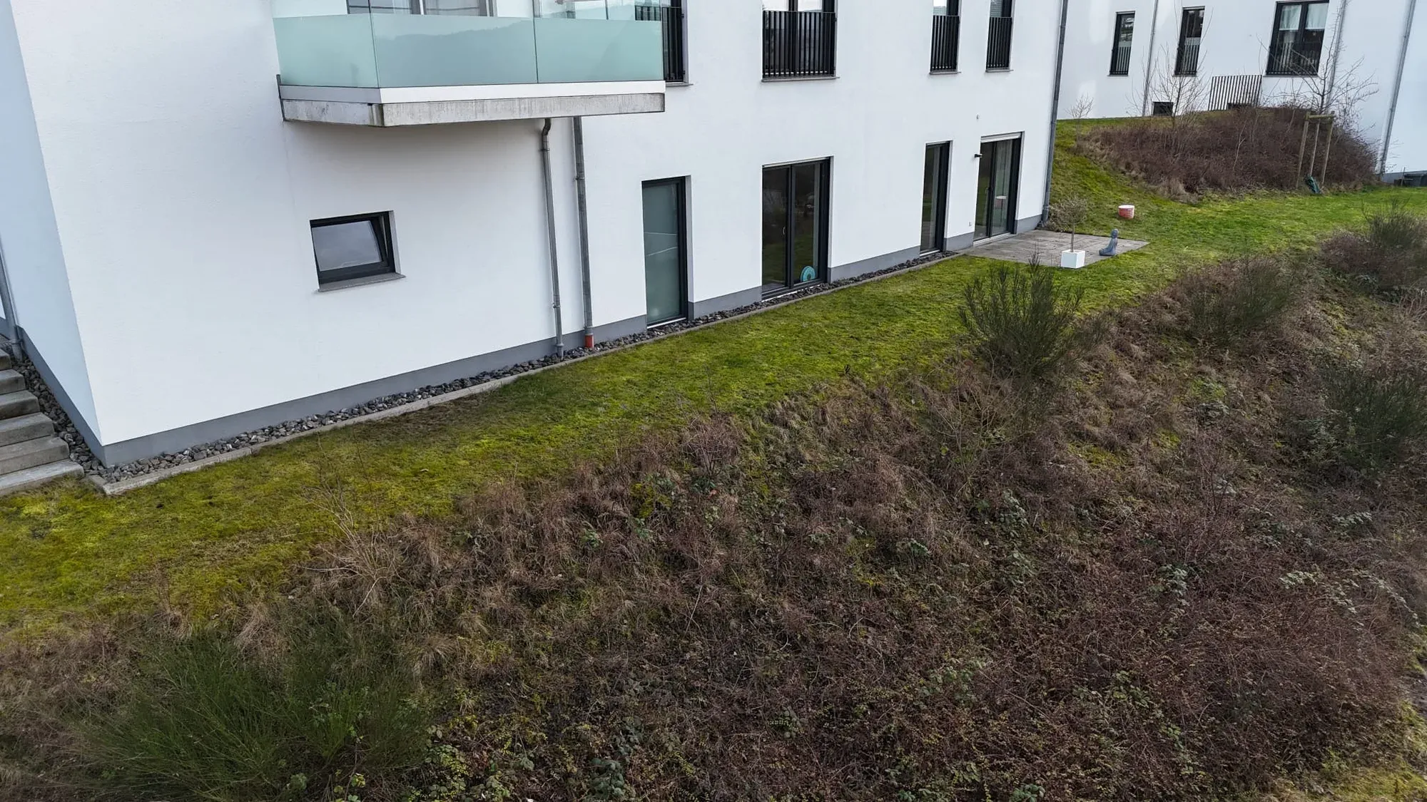 Vorher: Vorher: alte Plattenfläche und moosiger Rasen am Mehrfamilienhaus