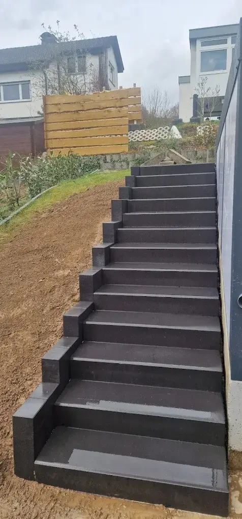 Anthrazitfarbene Außentreppe aus Beton im Garten